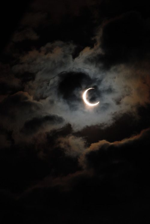Fin croissant de lune éclairé, partiellement voilé par les nuages